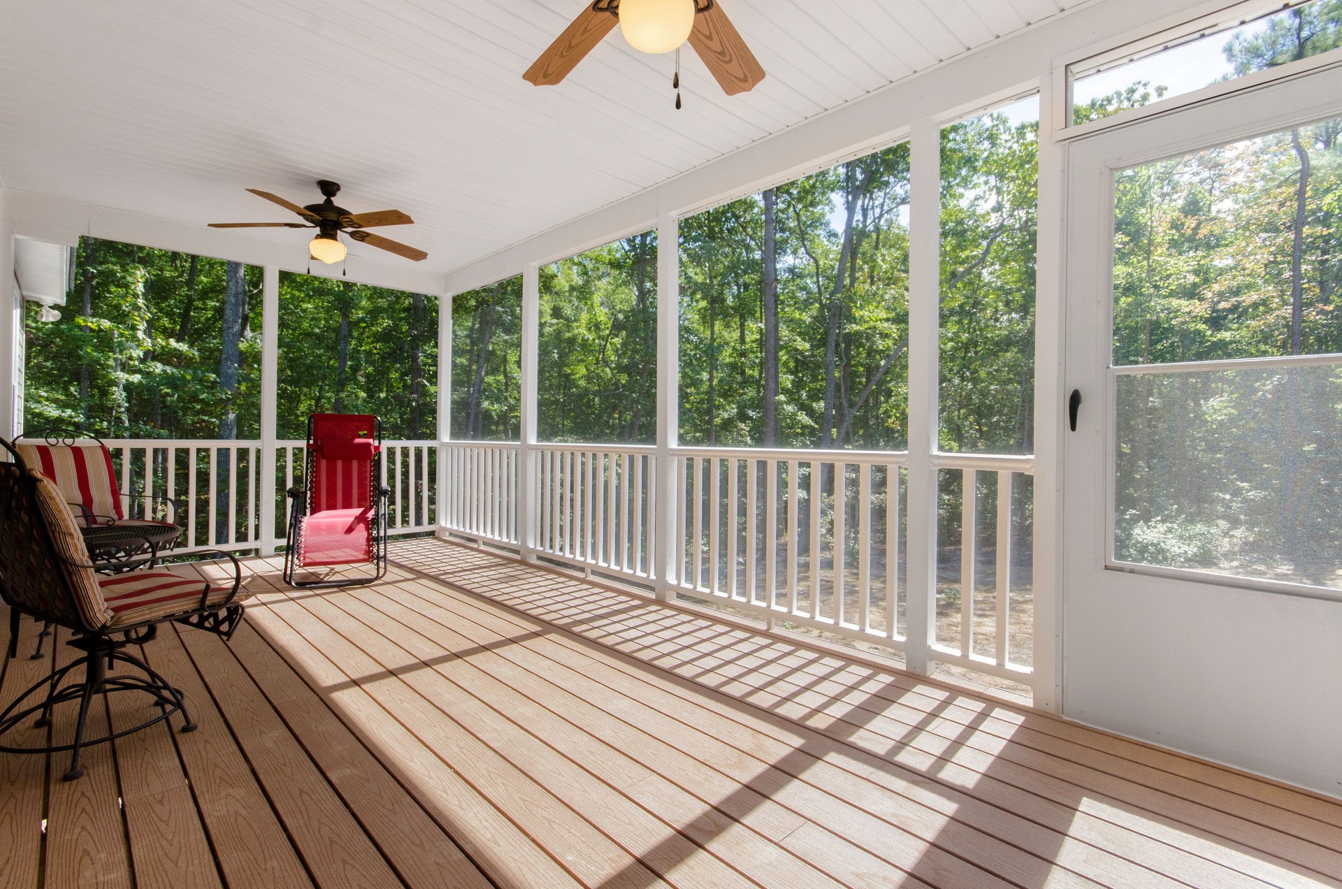 Screened-In Porch With Wooden Deck, Ceiling Fans, And Outdoor Furniture