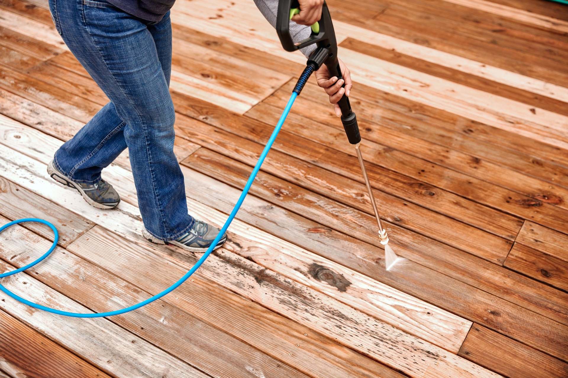 Woman Cleaning Wooden Terrace With A High Water Pressure Cleaner